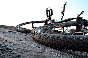 Imagem da Notícia Imagem de bicicleta caída no asfalto, vista a partir do pneu traseiro